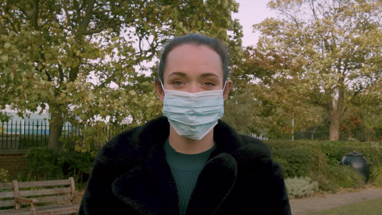 Female putting on medial facemask whilst looking to camera