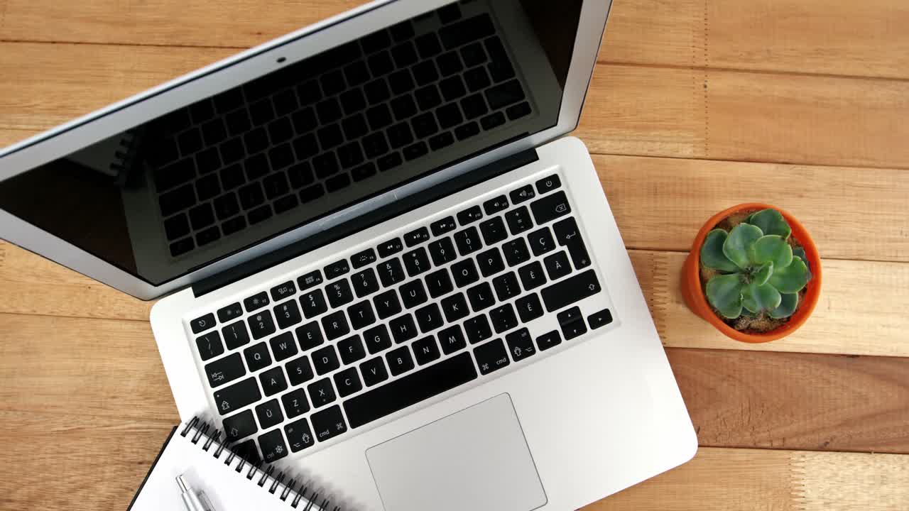 portátil con ratón, diario, bolígrafo y planta de maceta