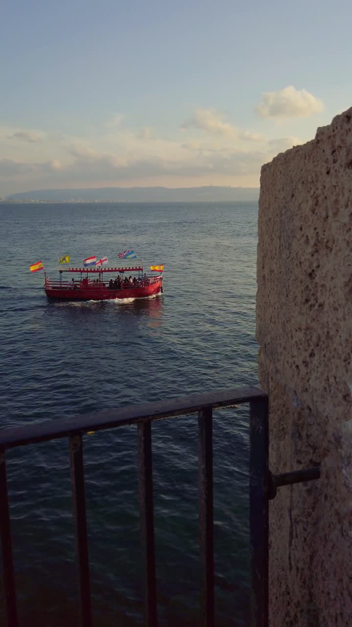 Red tourist boat sailing in the Mediterranean sea near Acre old city, Israel