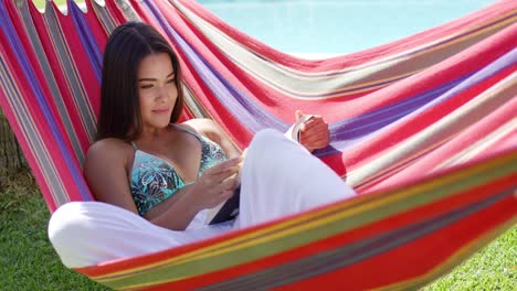 mujer relajada sentada en una hamaca con un libro