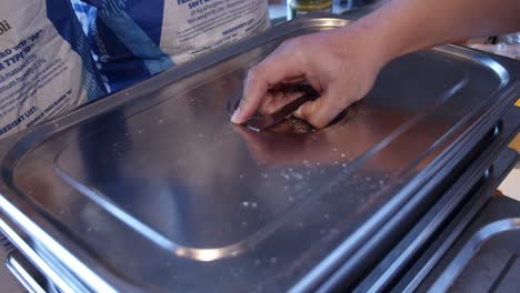 Chef-puts-the-pizza-dough-pieces-into-metal-tray-for-storage