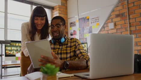 Graphic-designers-working-together-on-digital-tablet-at-desk-in-office-4k