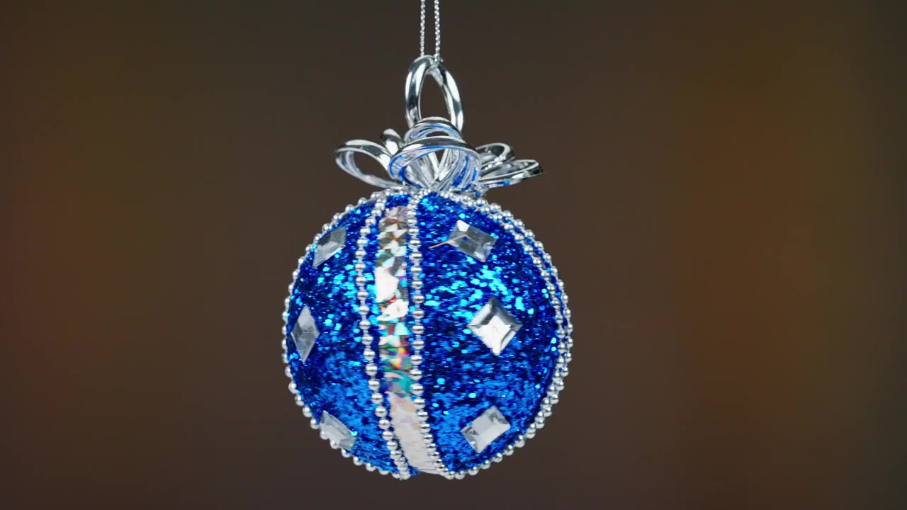 Gnistrende blå julekugle med glimmer og sølvdekorationer, der roterer
