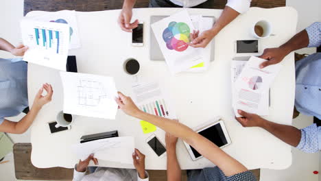 business people at a desk passing documents, overhead shot