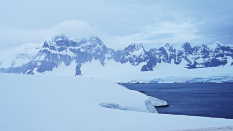 dramatic winter mountains and snow in antarctica with snowy snow covered scenery, big mountains in cold weather, antarctic peninsula coastal landscape on beautiful coast coastline