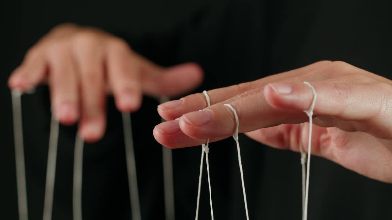 Close Up of Hands Manipulating White Strings Like a Puppeteer