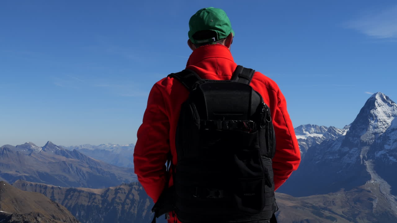 hombre con abrigo rojo admira las montañas jungfraujoch, conocidas como la cima de europa