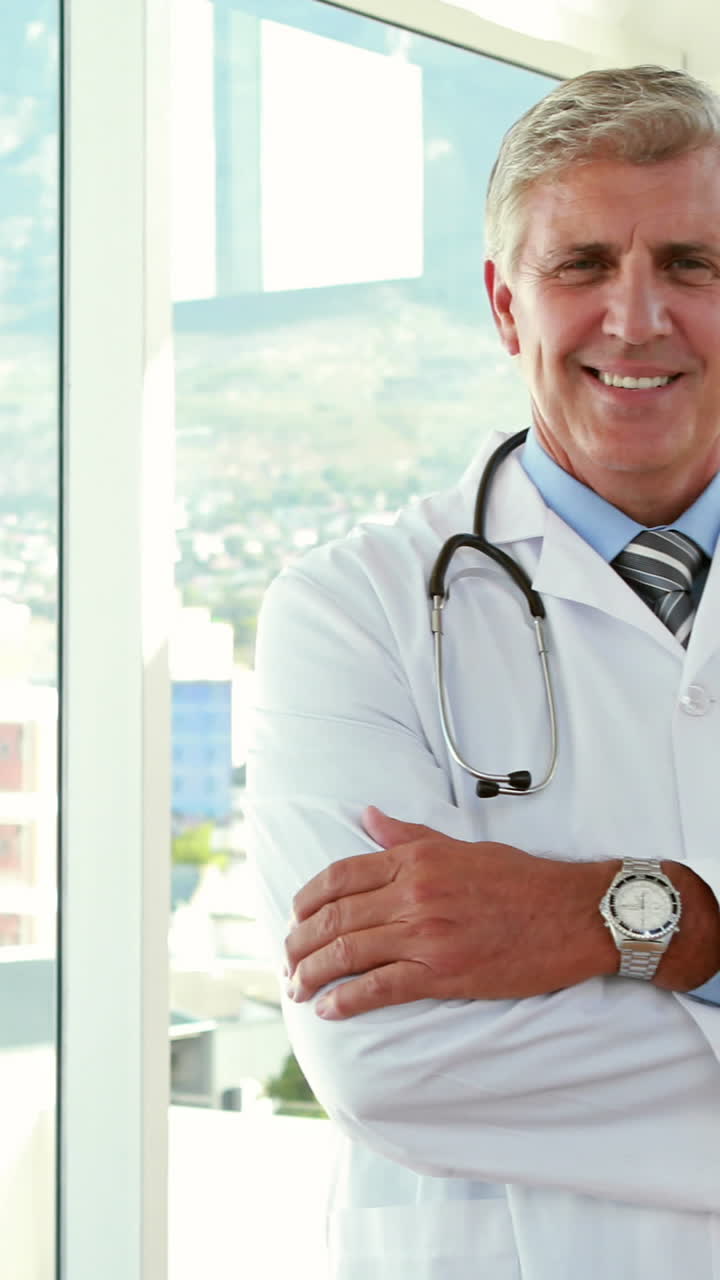 médico feliz mirando a la cámara con los brazos cruzados