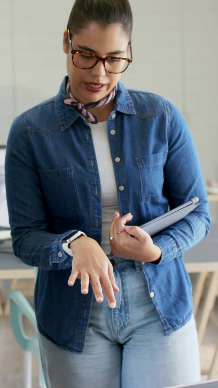 Video verticale: Reagisce a un collega che indica il laptop, donna in jeans che lavora in ufficio con un tablet.