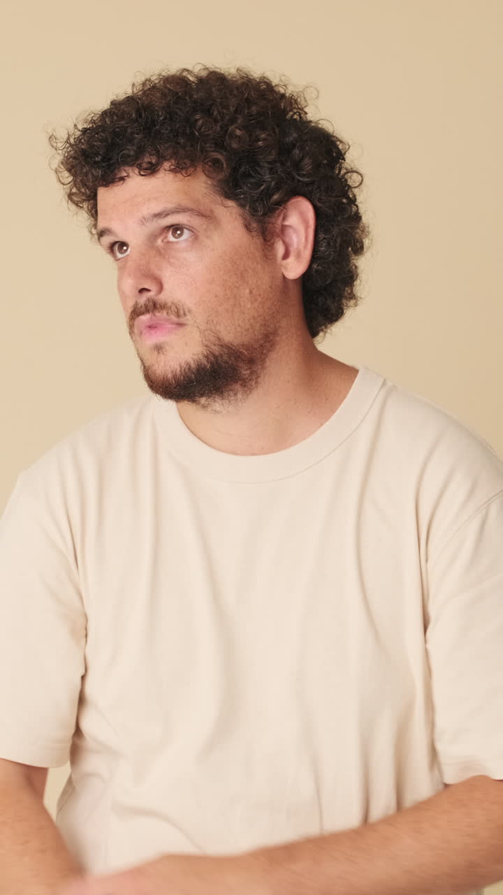Young Man with Curly Hair Looking Around and at Camera