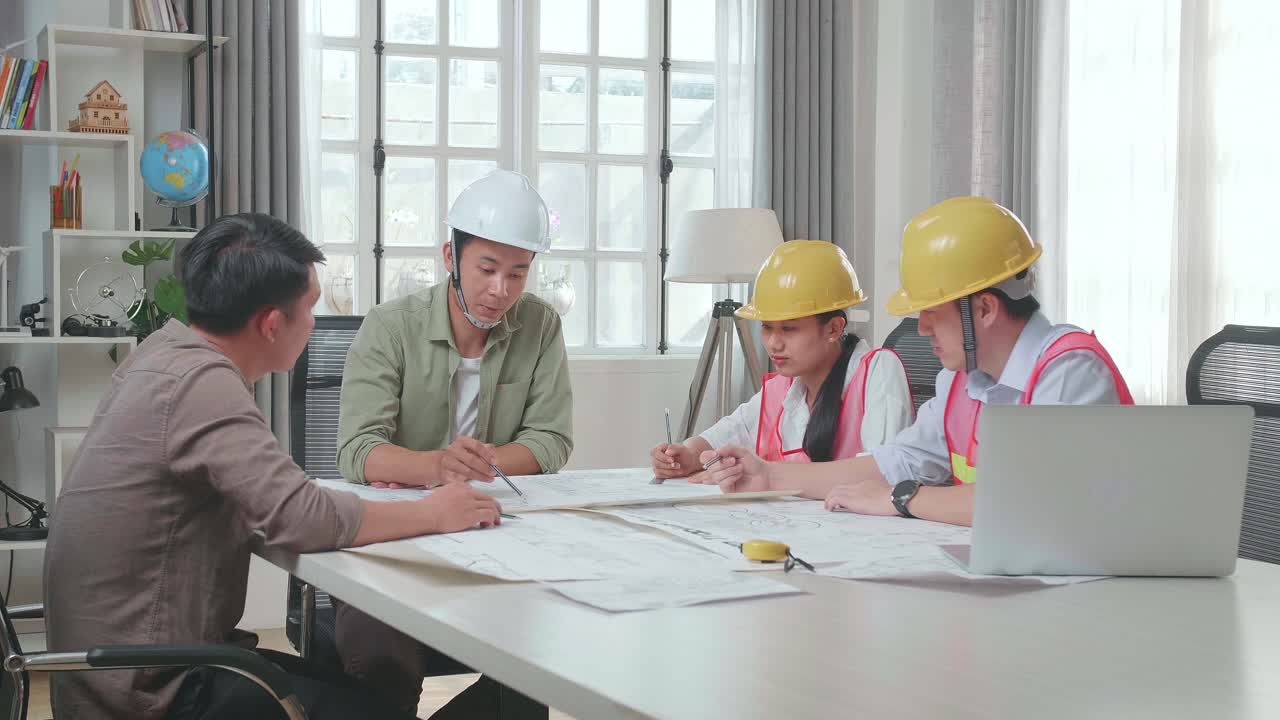 Three Asian Engineers With Helmets Presenting Work To A Man At The Office