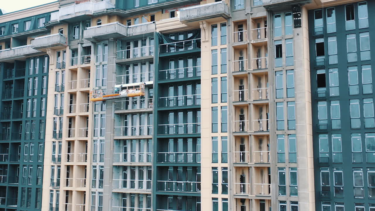Construction of a modern building in the city. Facade of multistorey apartment house with plastic windows in the city. Building of a new architecture.
