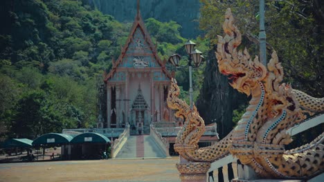 dragon scupltures at the entrance to a temple and another temple in the background between the mountains