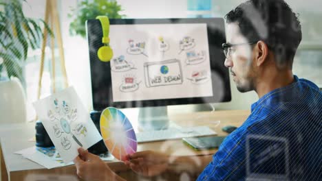 animación de iconos digitales sobre un diseñador gráfico masculino biracial que sostiene una paleta de colores en la oficina