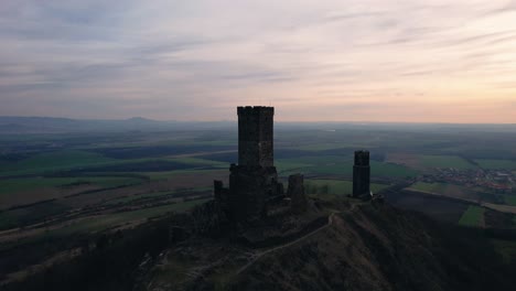 Cinematic-drone-view-pulling-away,-medieval-Hazmburk-Castle-towers-at-dusk