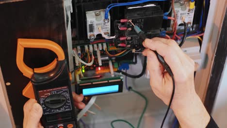 los electricistas ponen las manos a probar la corriente eléctrica en el panel de control. el ingeniero electricista trabaja midiendo el voltaje y la corriente de la línea eléctrica en el control del gabinete eléctrico.