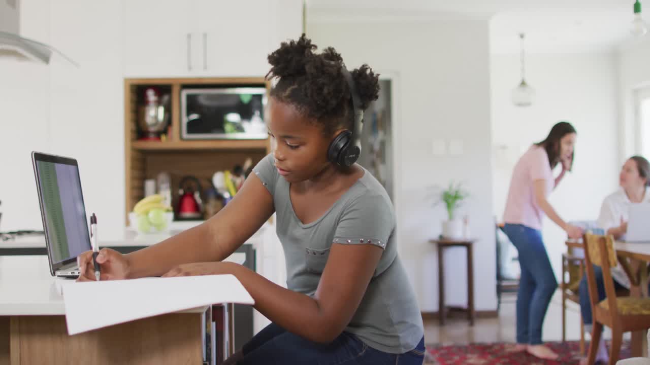 Happy african american girl using laptop for online lesson at home