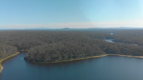 Toma-Aérea-Panorámica-A-Través-De-Un-Lago-En-El-Desierto-Australiano-Con-Montañas-En-El-Fondo