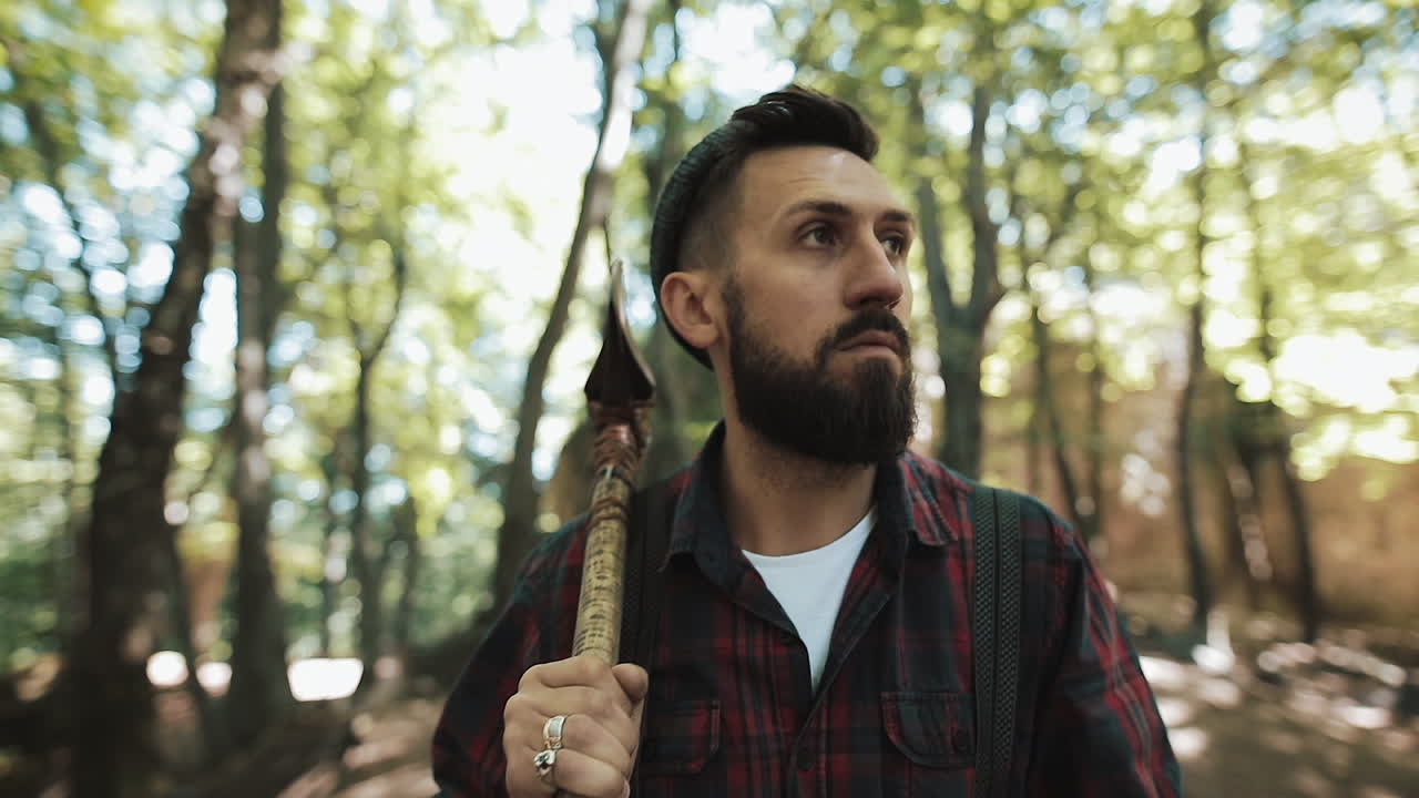 A bearded lumberjack with an axe in a forest