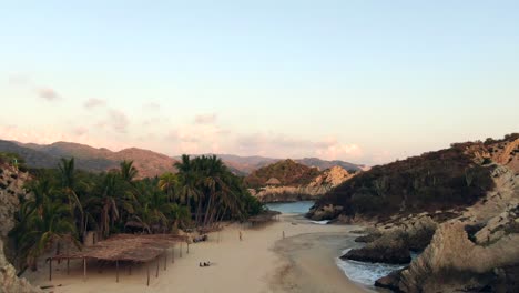 Gente-Caminando-En-La-Playa-De-Maruata,-Playa-De-Arena-Remota-Con-Paisaje-Rocoso-En-Michoacán,-México