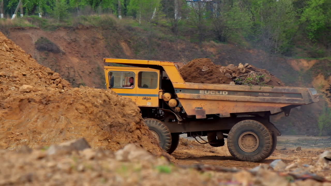 Quarry truck in background. Large yellow quarry dump trucks produce transportation