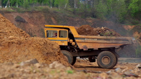 quarry truck in background. large yellow quarry dump trucks produce transportation