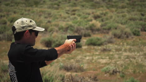 a male gunman with a baseball cap fires a handgun at targets in 120fps slow motion