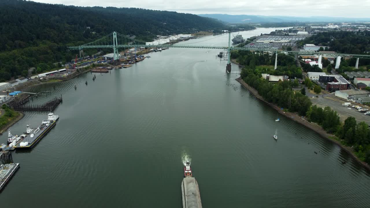 US, Oregon, Portland, St Johns, 2025-07-26 - Drone view of a barge being pushed by a tug on the Willamette River under the bridge