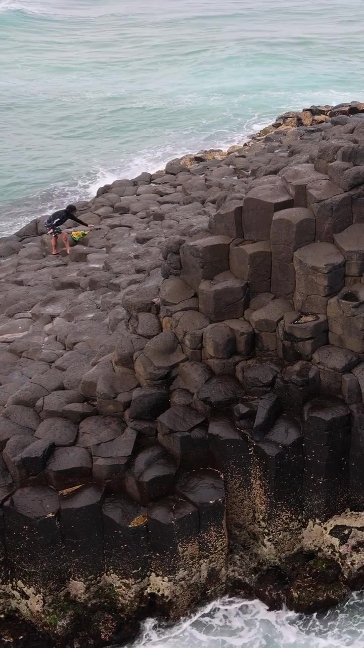 Ocean waves hitting a unique hexagonal rock structure