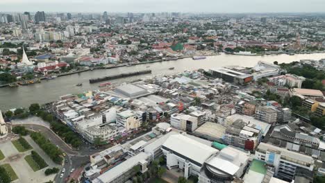 Aerial-of-Bangkok-old-town-with-cargo-boat-cruising-the-river-drone-cityscape