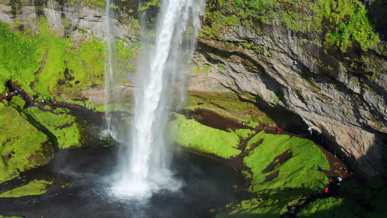 L'imponente acqua della cascata di Seljalandsfoss che scorre nel fiume in una soleggiata giornata estiva in Islanda