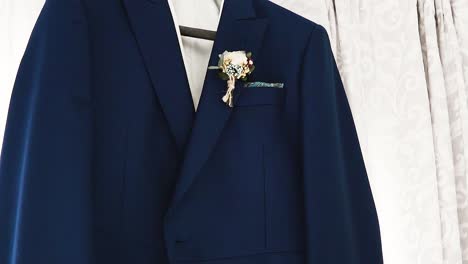 close up shot of blue navy formal jacket with pinned flower bouquet at wedding day