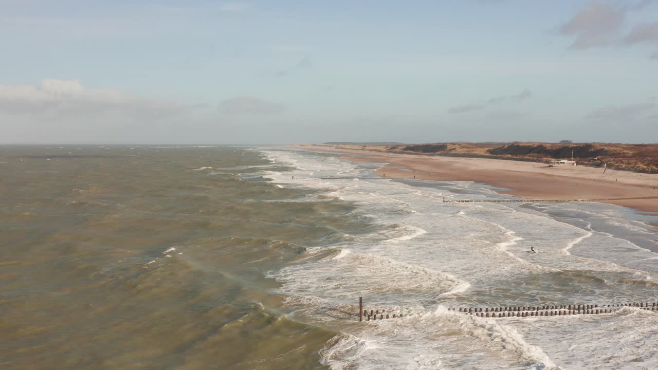 A kitesurfer in front of a empty beach during a cold winter day. Drone shot