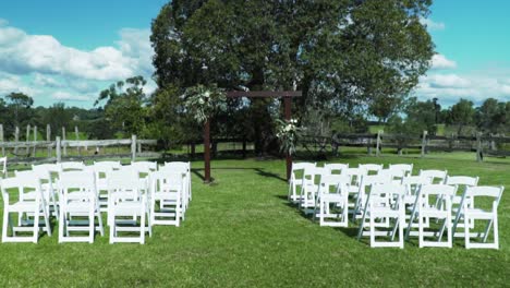 lugar de boda con arco de madera y sillas blancas para la ceremonia de boda al aire libre - plano general