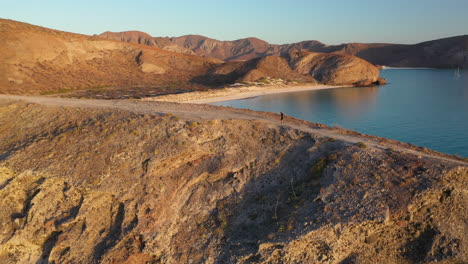 wide shot of man walking on ridge balandra beach, drone shot, rotating drone shot