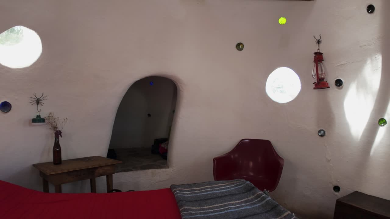 Eco-friendly earthen home interior showcasing a bedroom with earthy decor and cozy furniture, pullback over bed showcasing ceiling support beams