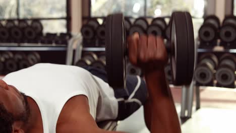 Man-lifting-heavy-dumbbell-at-gym