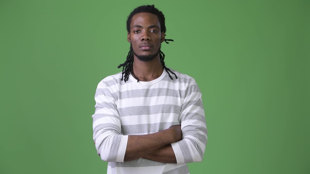 Giovane e affascinante uomo africano con i dreadlock su sfondo verde