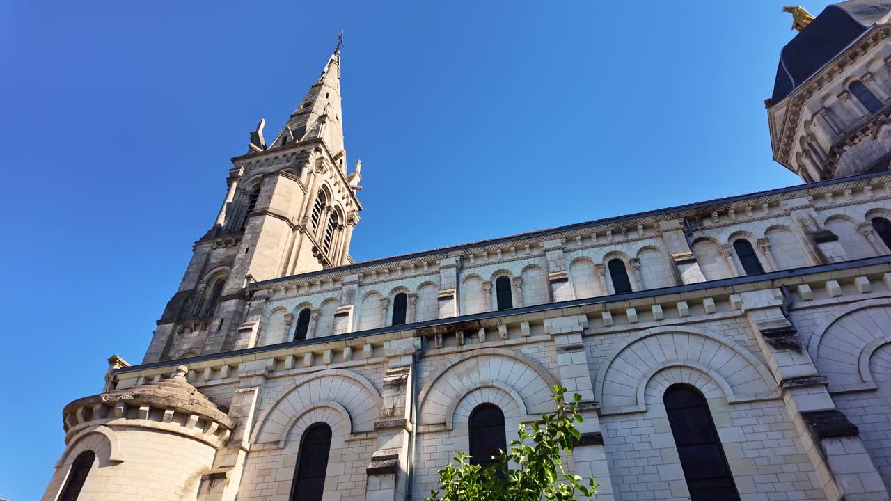 Wide pan around Notre-Dame cathedral in Châteauroux with surrounding buildings, establishing right to left towers