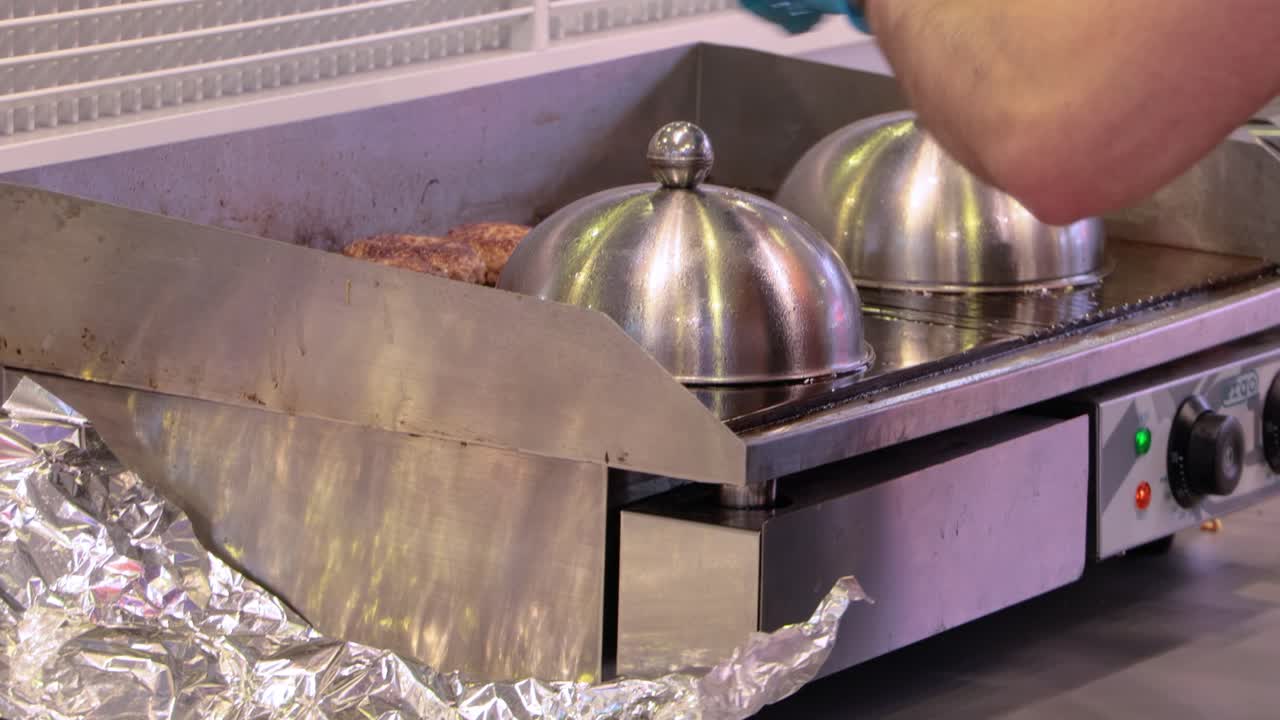 고기 패티는 뜨거운 프라이팬에서 요리됩니다. 스트리트 푸드, 셰프는 스파 ⁇ 라로 햄버거를 뒤집습니다.