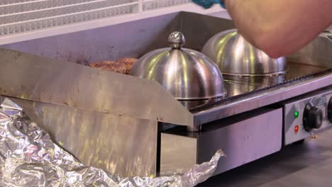la carne de res se cocina en una sartén caliente. comida callejera, el chef lanza hamburguesas con una espátula.