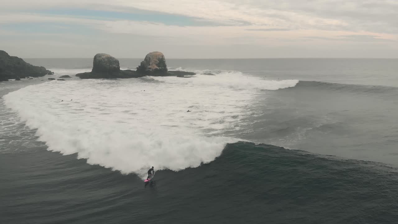 toma aérea de un surfista profesional en una tabla rosa montando una gran ola en pichilemu, chile-4k