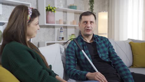 un hombre ciego y su esposa charlan. son felices y en casa.