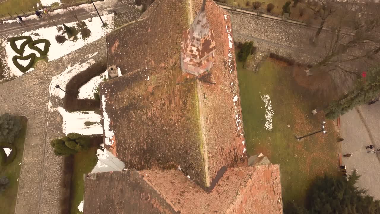 una toma de drones, con encuadre ortomosaico y movimiento hacia adelante, que captura la azotea de una arquitectura antigua en la ciudad de sighisoara en una tarde