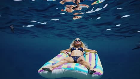 woman relaxing on inflatable raft underwater