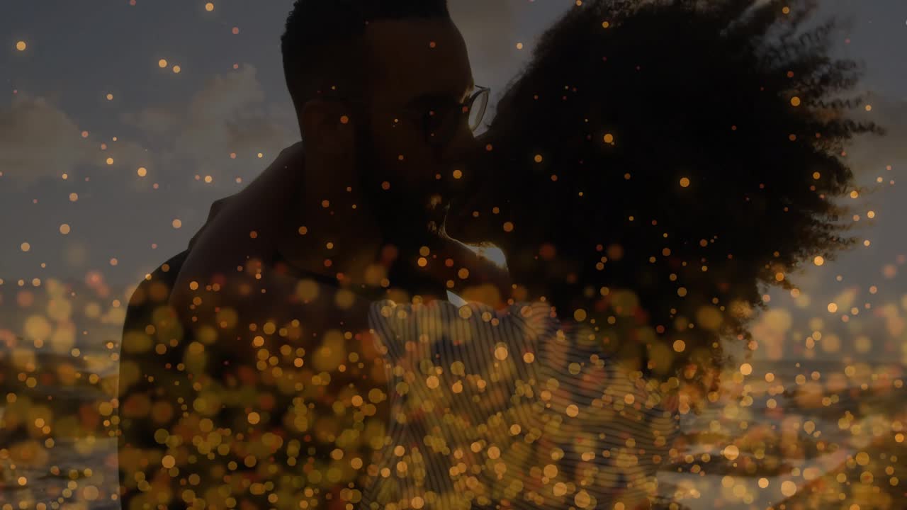 Film montrant le soleil approchant l'horizon de l'océan, créant un éclat doré au milieu d'un couple soulevant une femme qui l'embrasse.