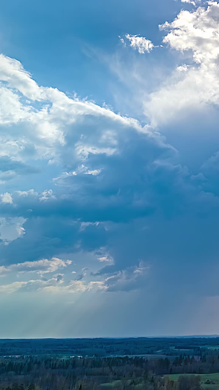 Soft blue sky clouds rolling and dissolving into white light, slow atmospheric motion above forest backlit hiding sun, vertical aerial static