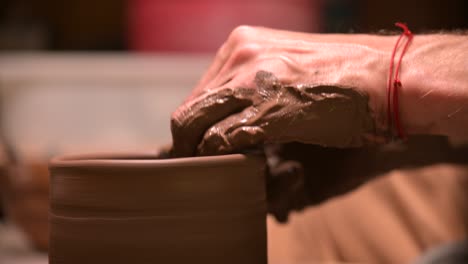 close-up of a man potter making a clay bowl on a potter's wheel from clay