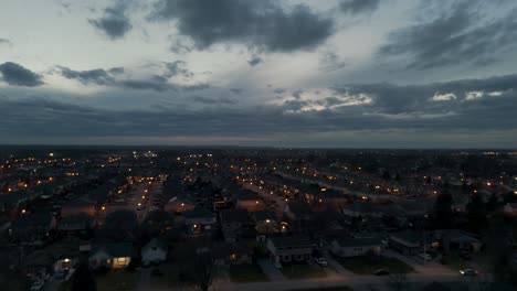 Drohnenaufnahme-Von-Wolken,-Die-In-Der-Abenddämmerung-über-Einen-Vorort-Ziehen,-Während-Autos-Nach-Hause-Kommen