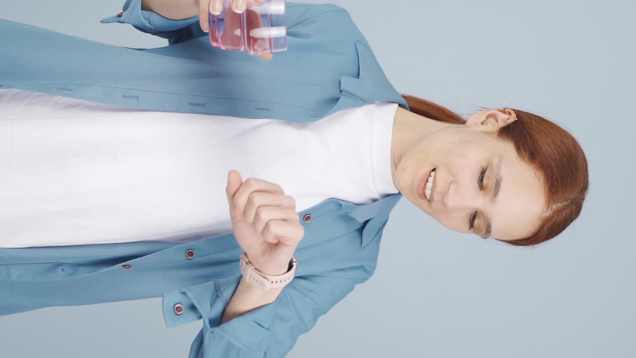 video vertical de la mujer que bebe agua a intervalos regulares. la mujer busca la curación.